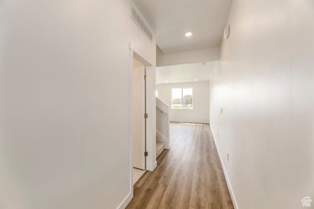 Corridor featuring light wood finished floors, baseboards, stairs, and recessed lighting