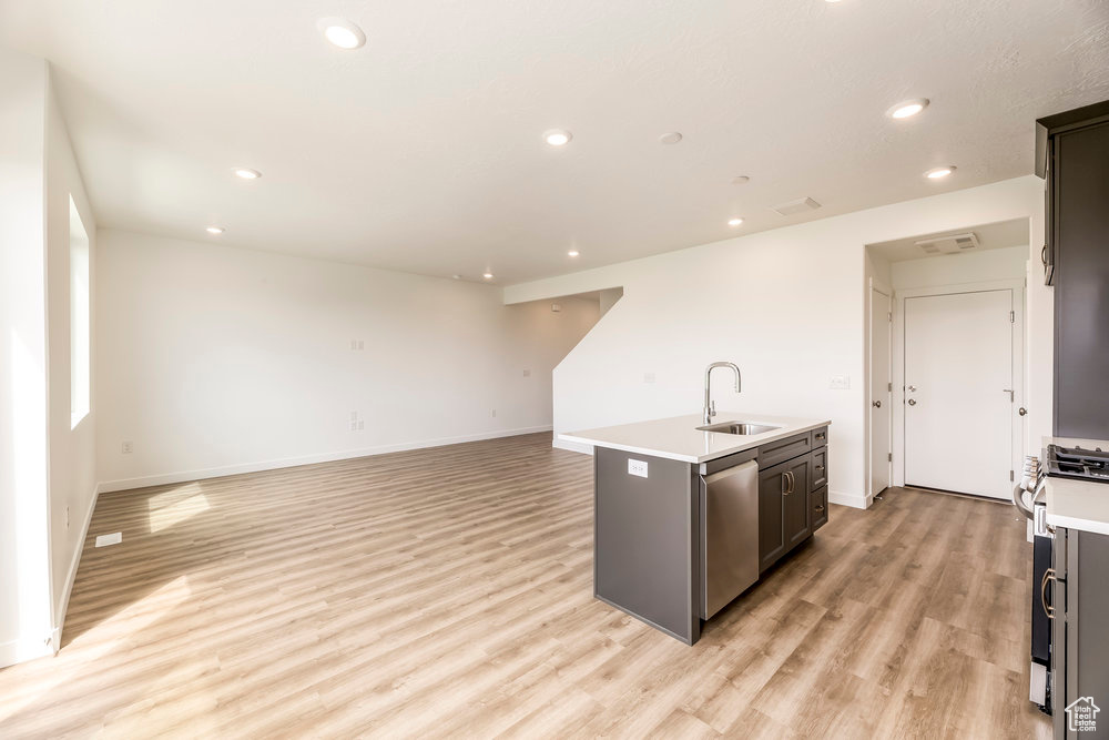 Kitchen featuring a sink, stainless steel appliances, a kitchen island with sink, light wood finished floors, and recessed lighting