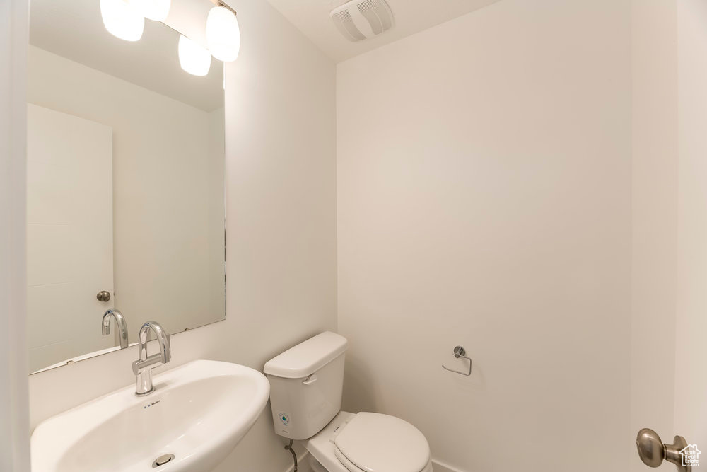 Half bathroom with a sink, toilet, and baseboards