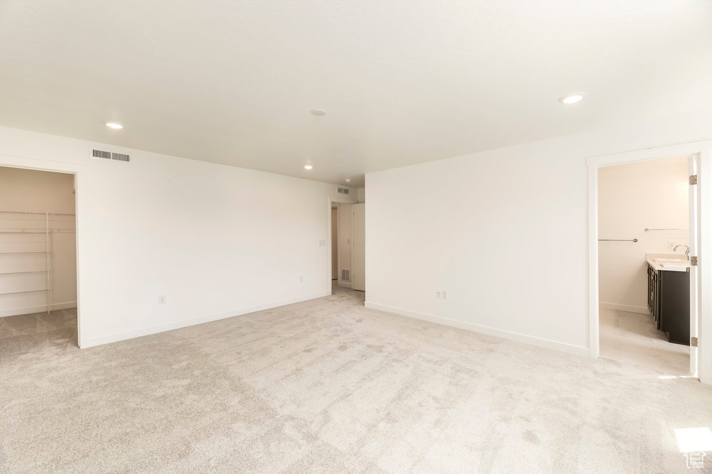 Unfurnished room featuring recessed lighting, light colored carpet, a sink, and baseboards