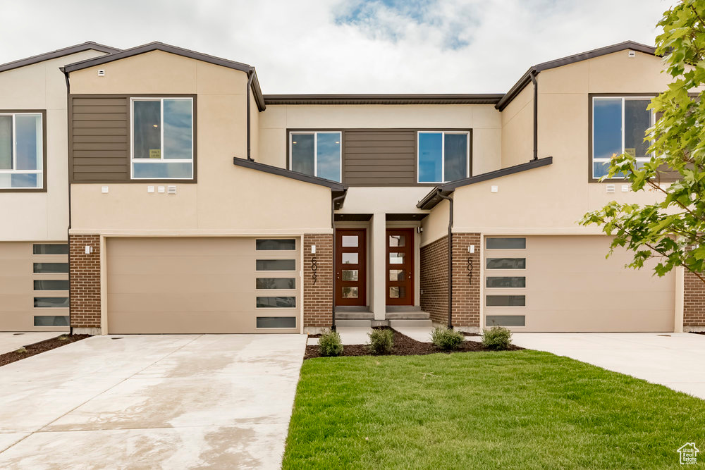 View of front of home featuring an attached garage, concrete driveway, and stucco siding