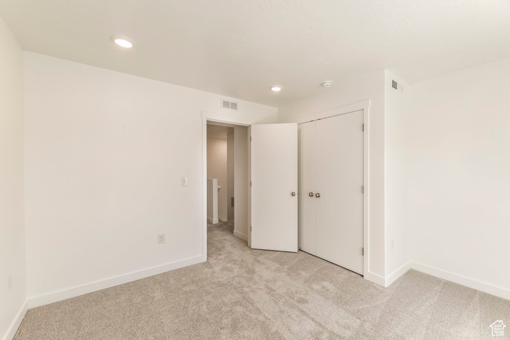 Unfurnished bedroom with light colored carpet, baseboards, recessed lighting, and a closet
