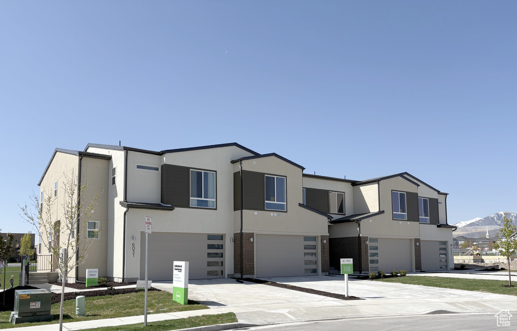 View of front facade featuring an attached garage, driveway, stucco siding, a mountain view, and brick siding