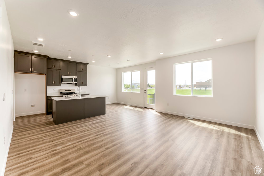 Kitchen with appliances with stainless steel finishes, baseboards, open floor plan, a sink, and recessed lighting