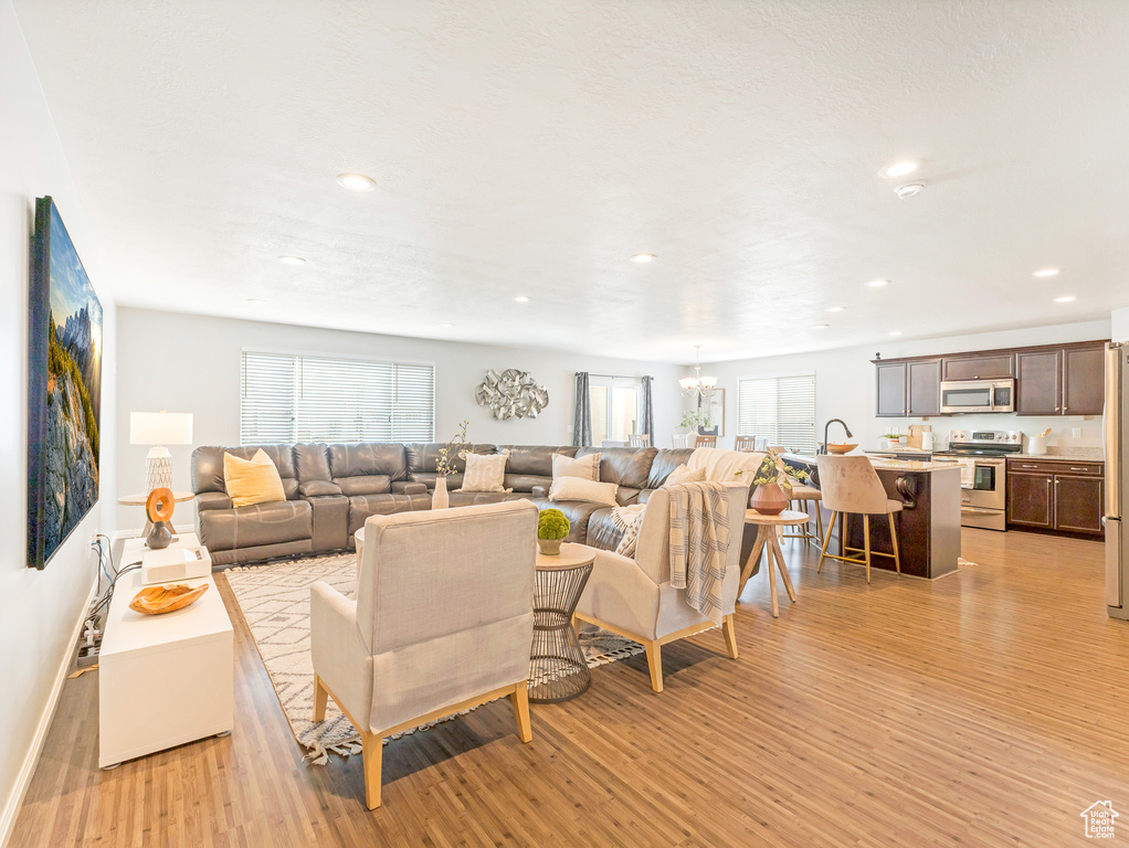 Living area with light wood finished floors, plenty of natural light, a chandelier, recessed lighting, and baseboards