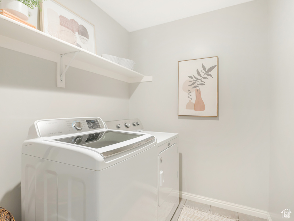 Laundry room with separate washer and dryer, light tile patterned floors, and baseboards