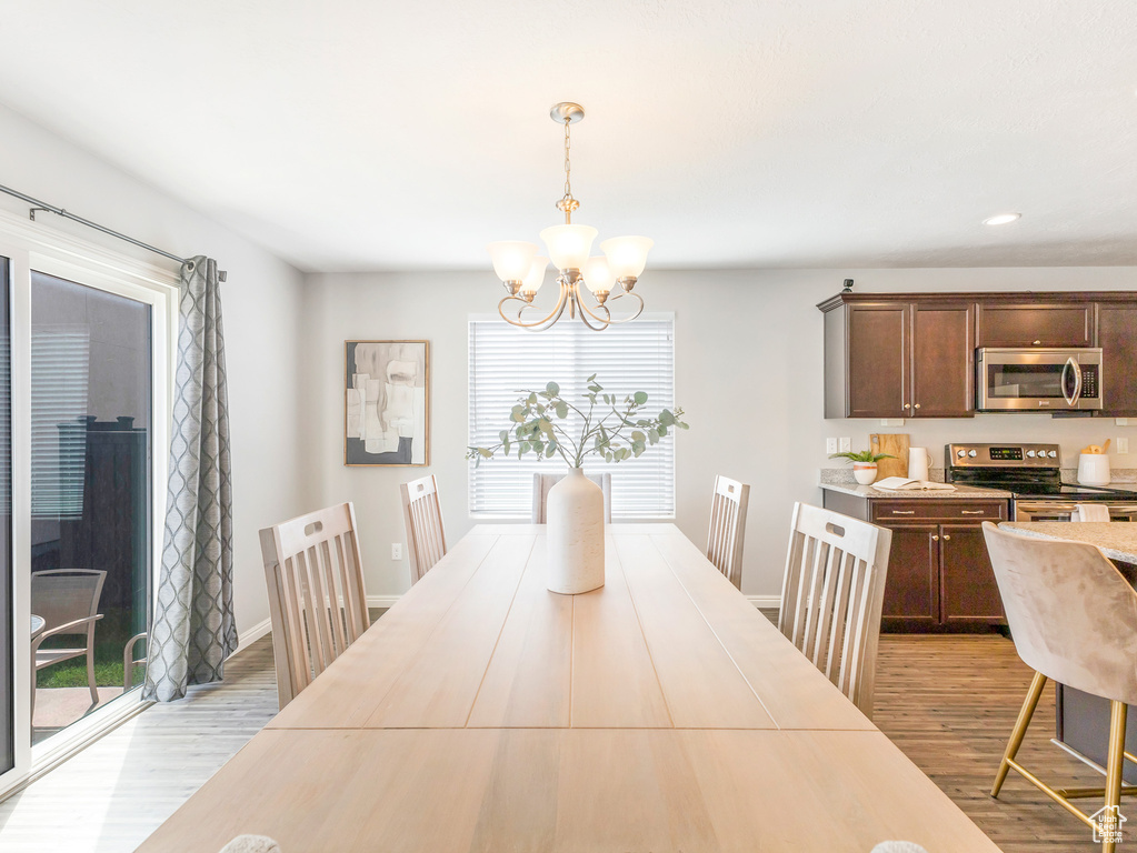 Dining room with a chandelier, light wood-style floors, recessed lighting, and baseboards