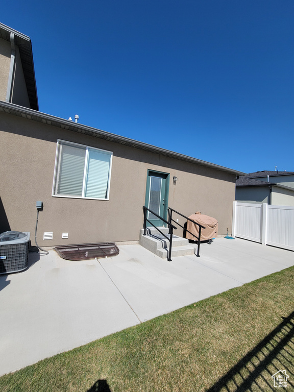 Rear view of property with fence, a patio, stucco siding, and cooling unit