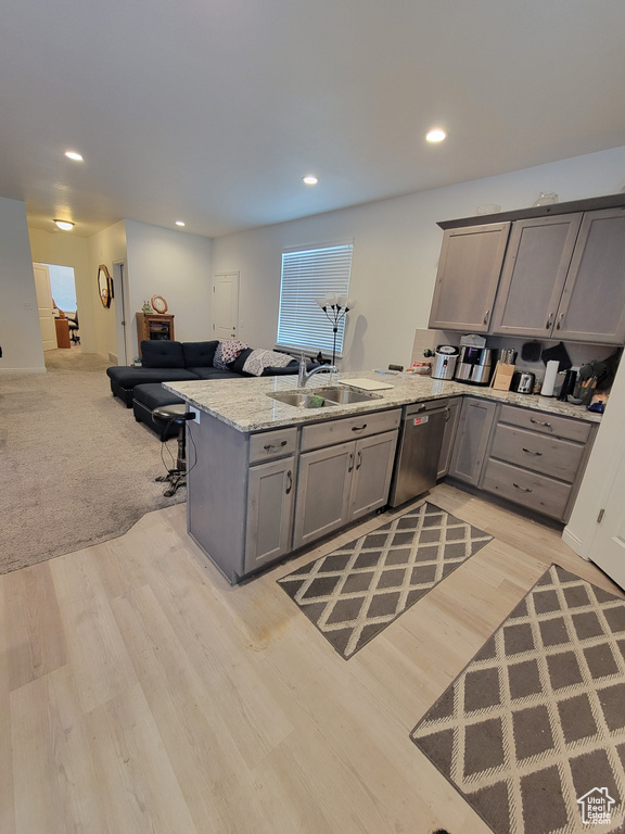 Kitchen featuring a peninsula, a sink, open floor plan, gray cabinets, and stainless steel dishwasher