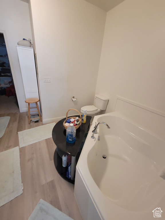 Bathroom with baseboards, a garden tub, and wood finished floors