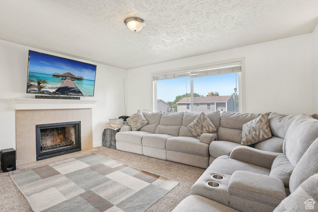 Living area featuring carpet flooring, a fireplace, and a textured ceiling