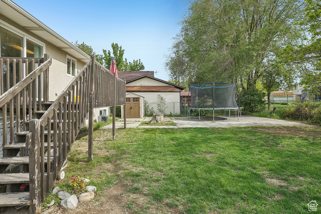 View of yard featuring a trampoline, a shed, stairway, an outdoor structure, and a patio