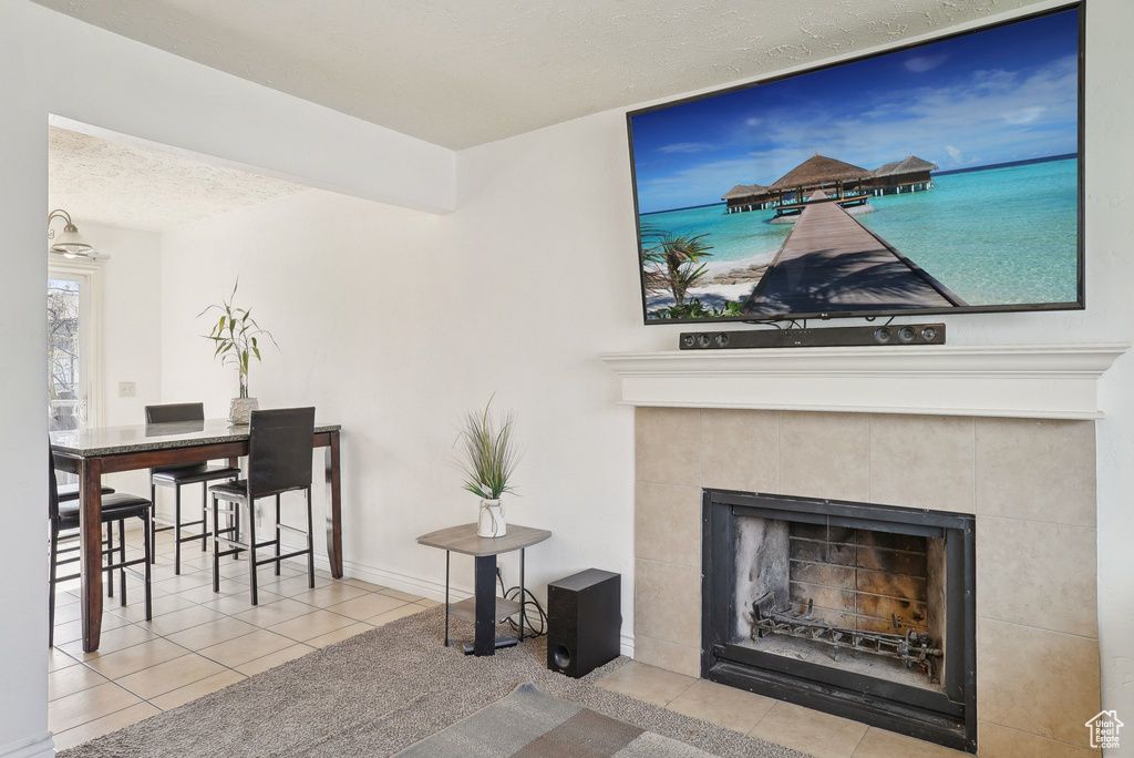 Living area with tile patterned floors, a textured ceiling, and a tiled fireplace