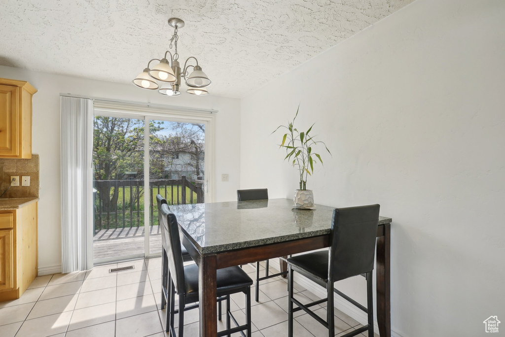 Dining room featuring a chandelier, light tile patterned floors, a textured ceiling, and baseboards