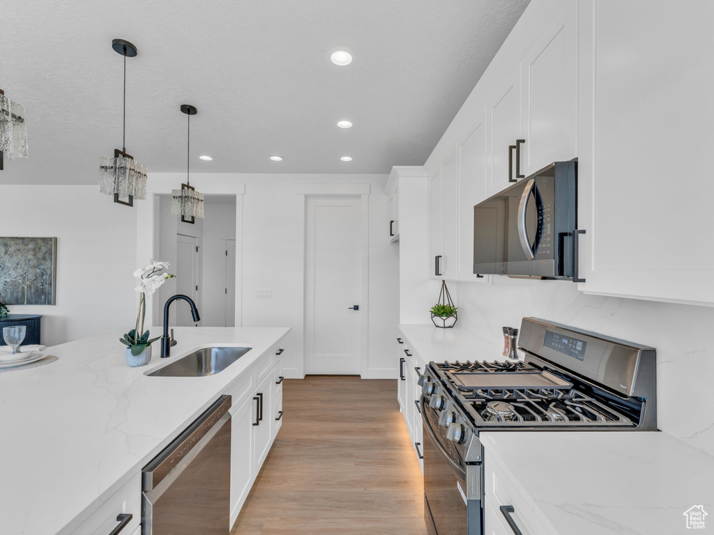 Kitchen with stainless steel appliances, a sink, white cabinetry, a chandelier, and recessed lighting