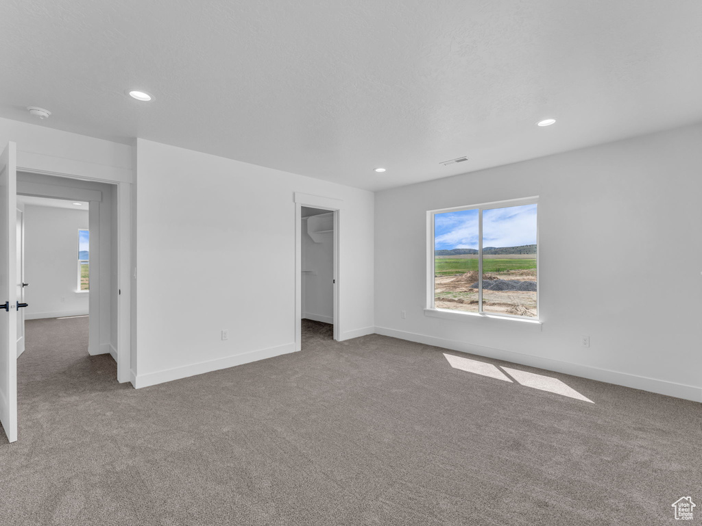 Unfurnished bedroom featuring carpet flooring, recessed lighting, baseboards, and a walk in closet