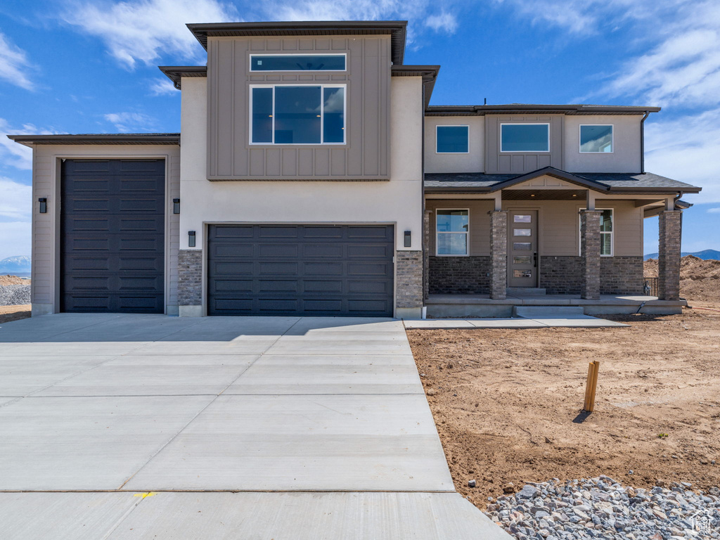 View of front of home with concrete driveway, board and batten siding, a garage, and covered porch
