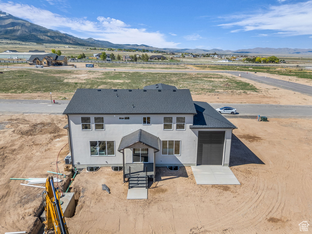 Back of house featuring a mountain view, a shingled roof, and stucco siding