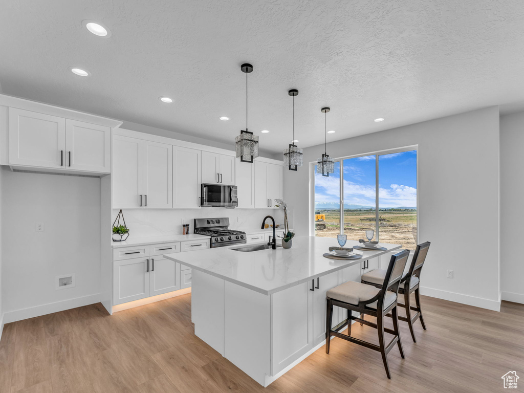 Kitchen featuring appliances with stainless steel finishes, a sink, baseboards, recessed lighting, and white cabinetry