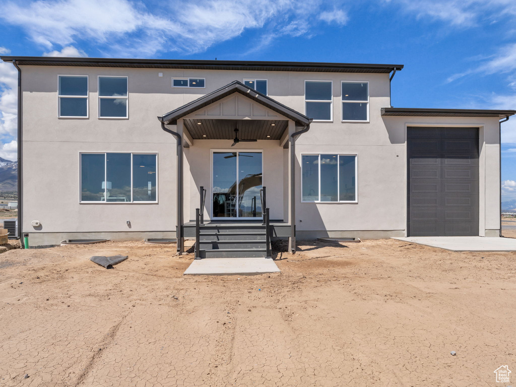 View of front facade featuring stucco siding, a garage, and a ceiling fan
