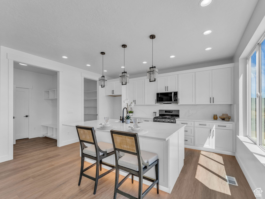 Kitchen featuring stainless steel appliances, light wood-type flooring, light countertops, white cabinetry, and recessed lighting