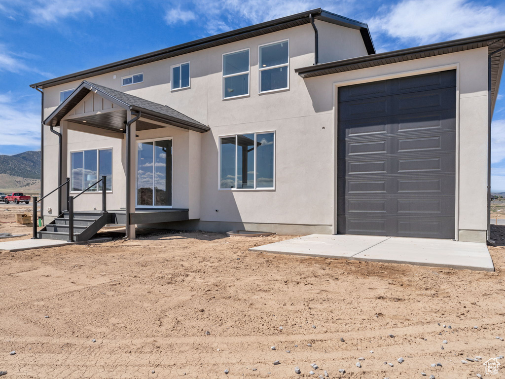 Rear view of house featuring stucco siding, an attached garage, and a mountain view