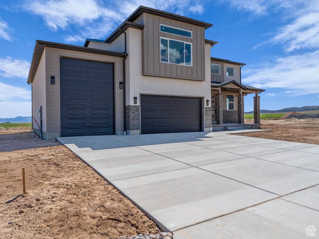 Modern home with concrete driveway, stone siding, board and batten siding, and a garage