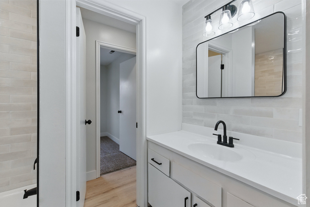 Bathroom featuring tasteful backsplash, wood finished floors, vanity, and baseboards