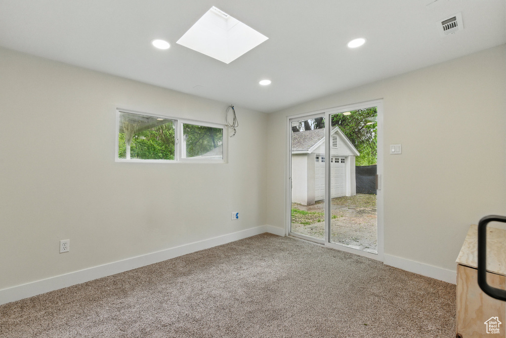 Unfurnished room featuring baseboards, carpet floors, a skylight, and recessed lighting