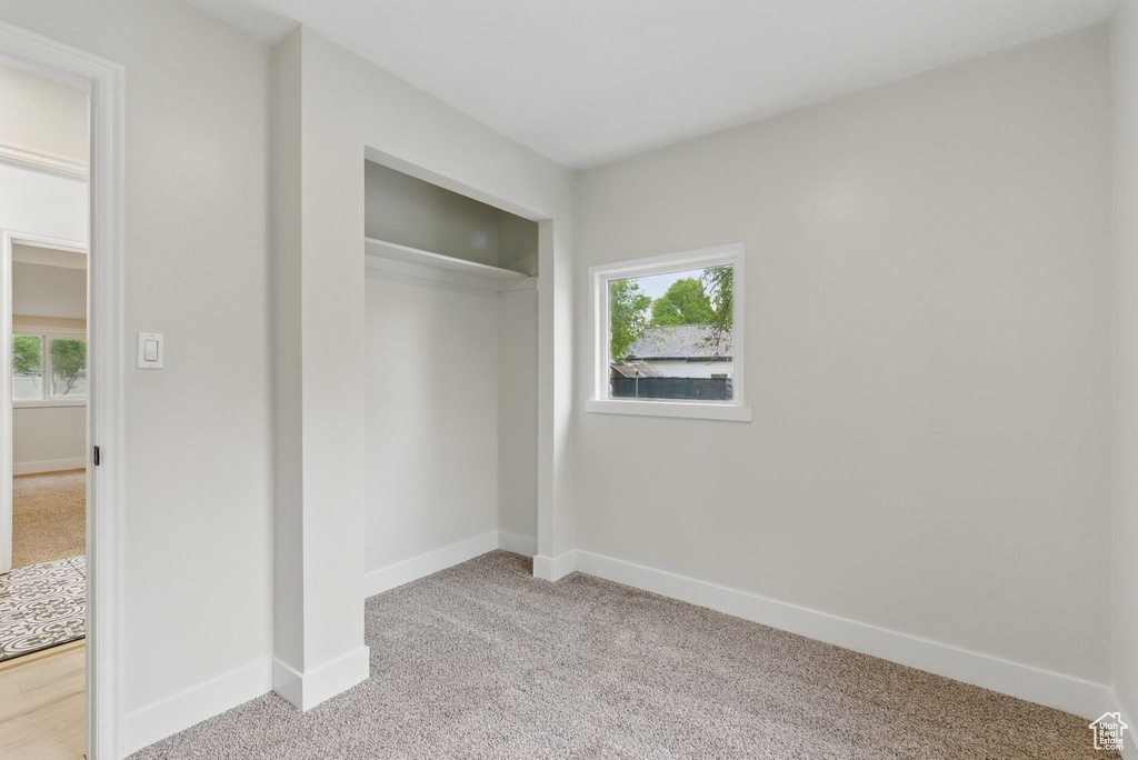 Unfurnished bedroom featuring light carpet, baseboards, and a closet