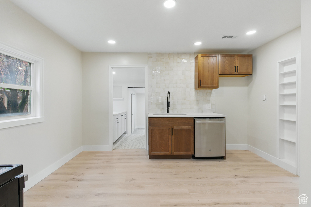 Kitchen featuring a sink, stainless steel dishwasher, light wood-type flooring, brown cabinets, and recessed lighting