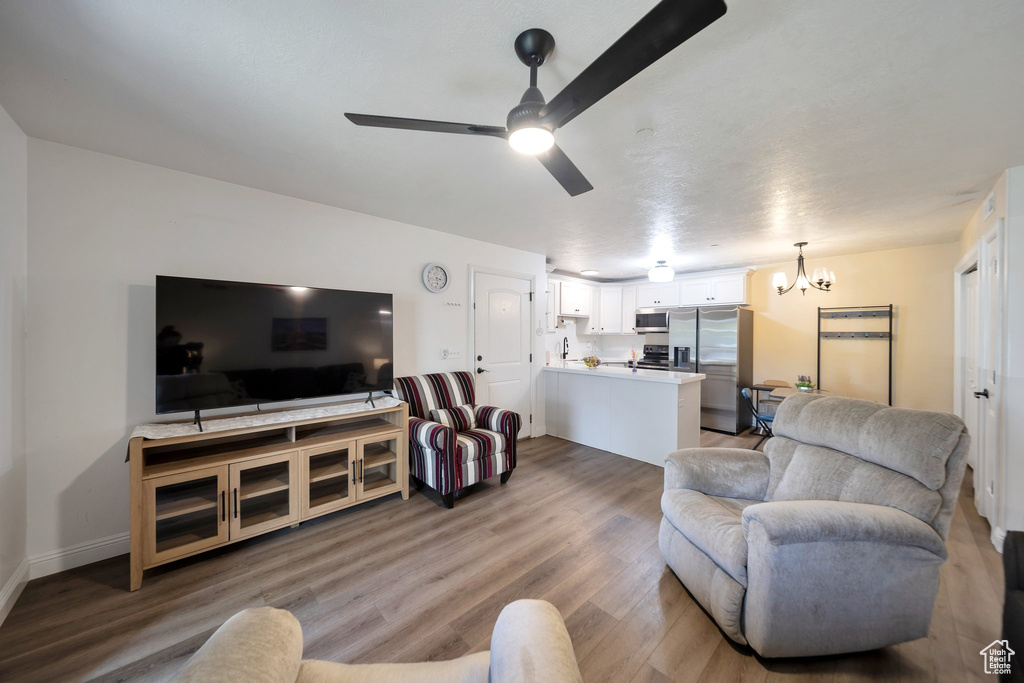 Living room with a chandelier, wood finished floors, and a ceiling fan