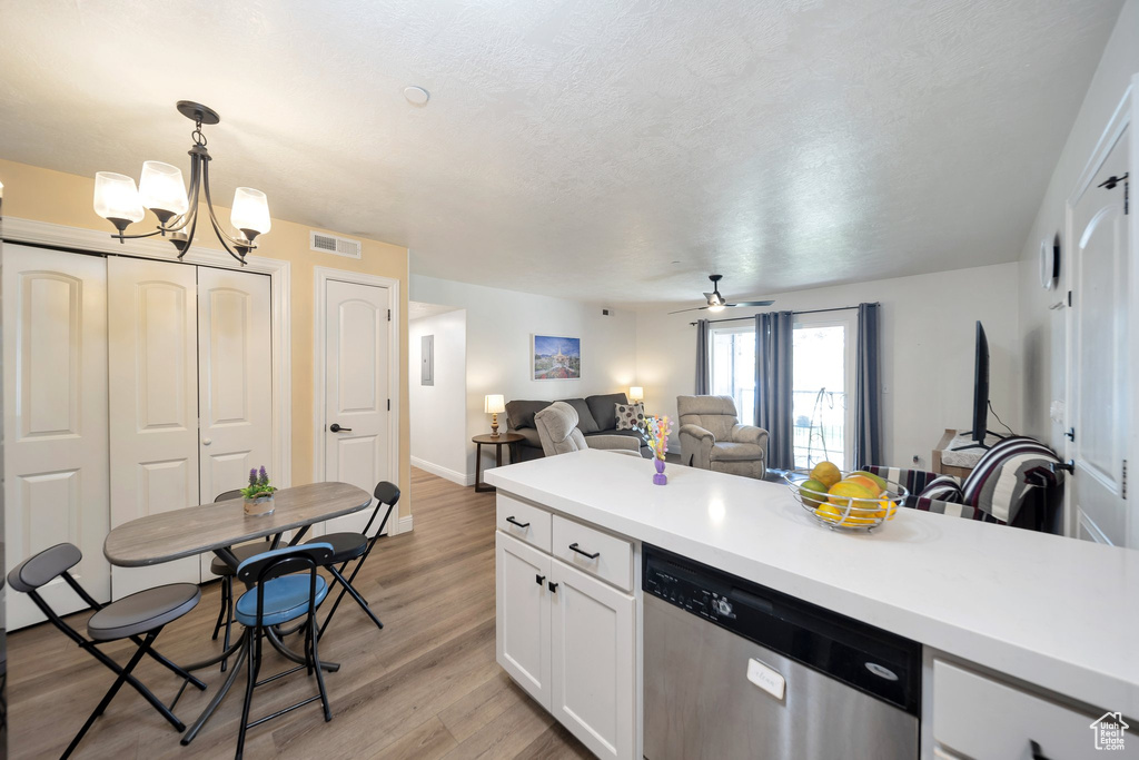 Kitchen with dishwasher, open floor plan, white cabinets, light countertops, and a chandelier