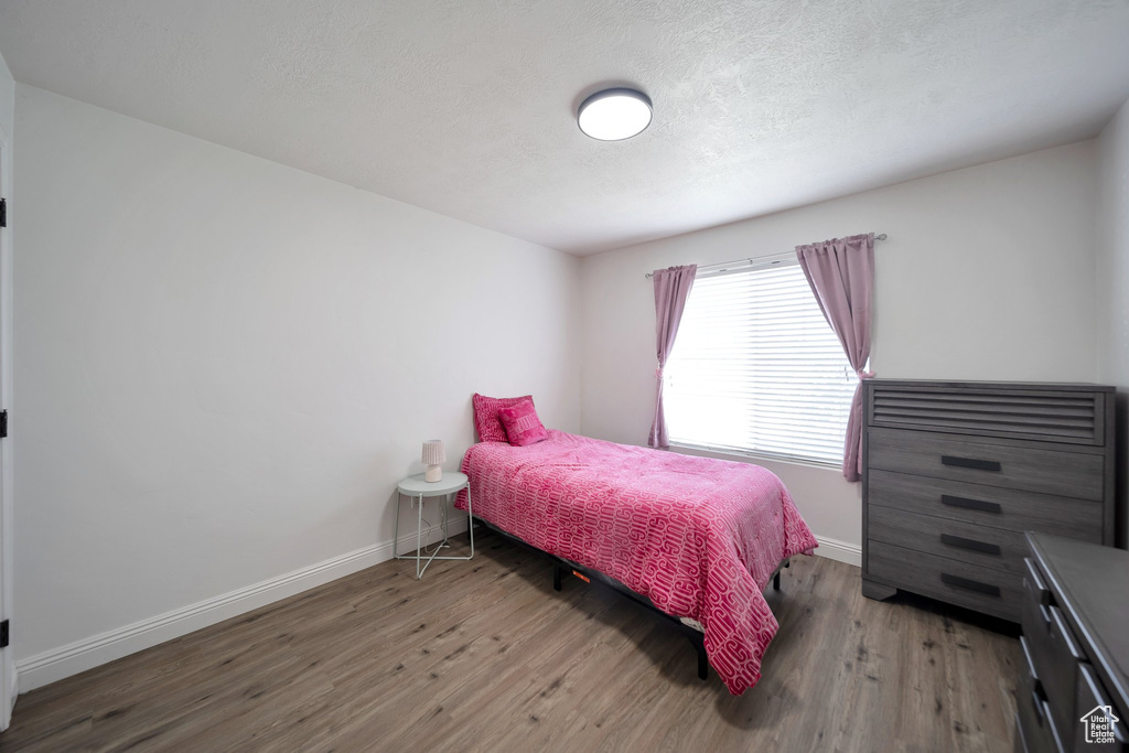 Bedroom featuring wood finished floors, baseboards, and a textured ceiling