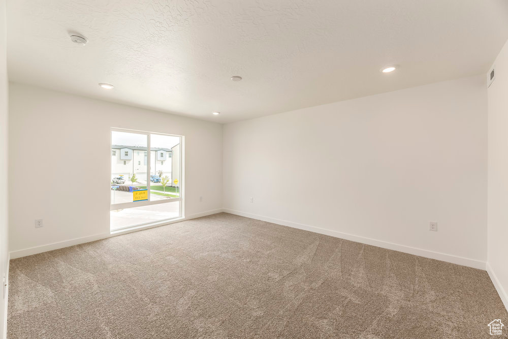 Carpeted spare room with baseboards, a smoke detector, and recessed lighting