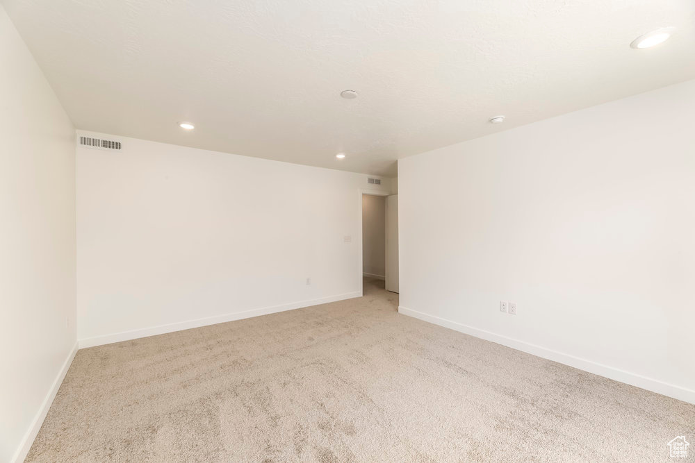 Spare room featuring recessed lighting, light colored carpet, and baseboards