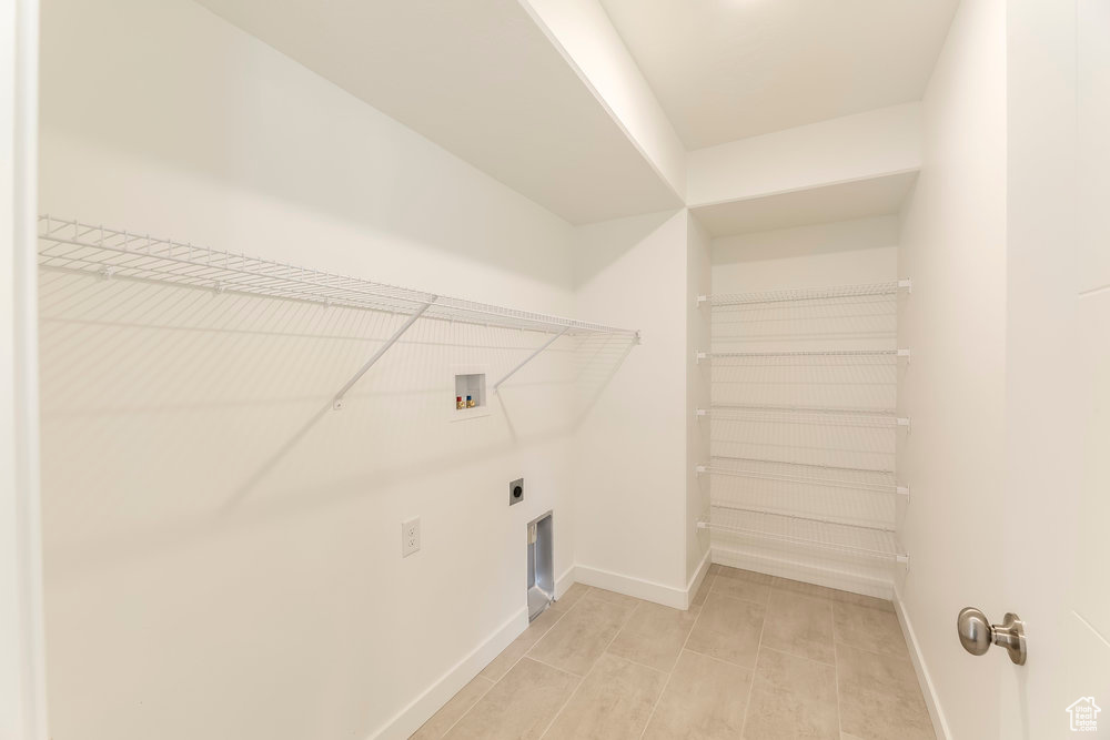Laundry area with hookup for a washing machine, electric dryer hookup, baseboards, and light tile patterned floors