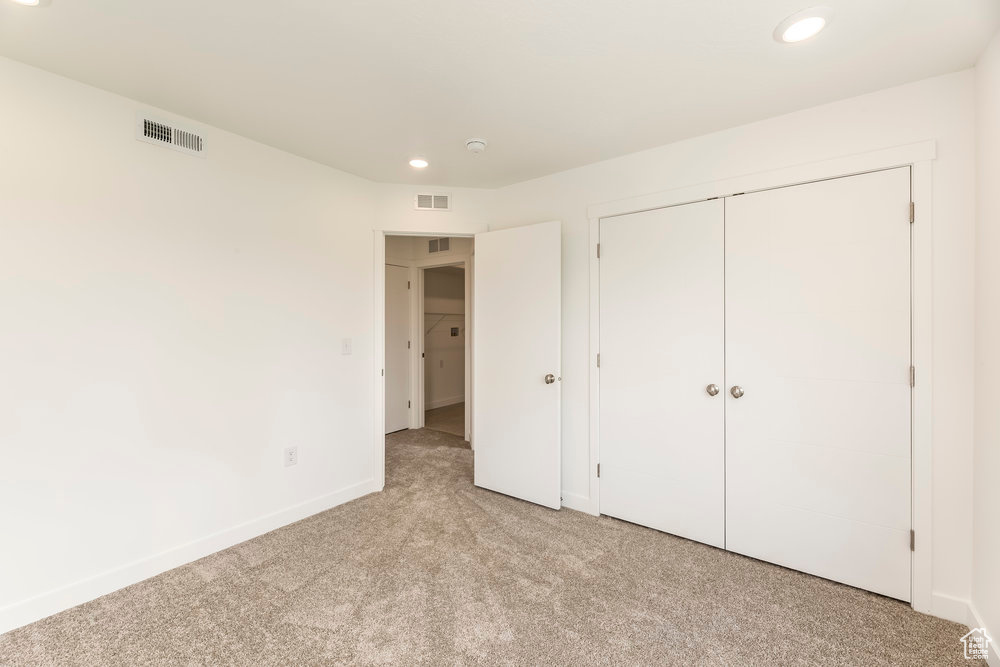 Unfurnished bedroom with light carpet, recessed lighting, baseboards, and a closet