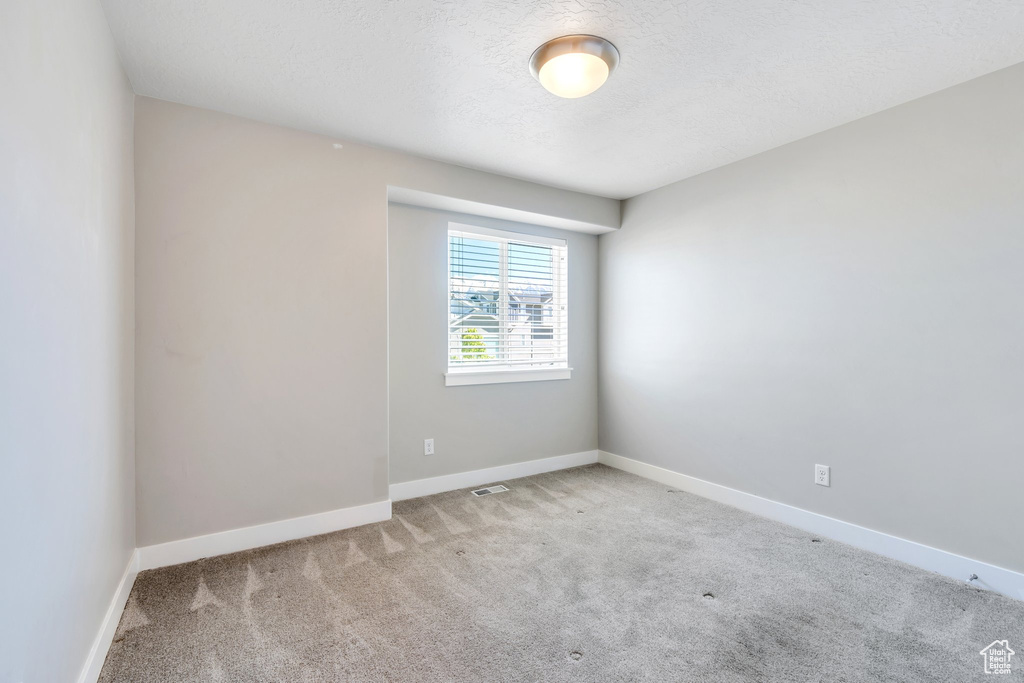 Carpeted empty room with baseboards and a textured ceiling