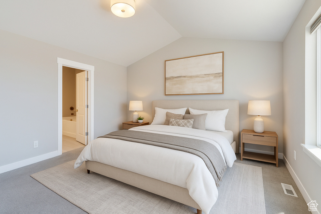 Carpeted bedroom featuring vaulted ceiling, connected bathroom, and baseboards
