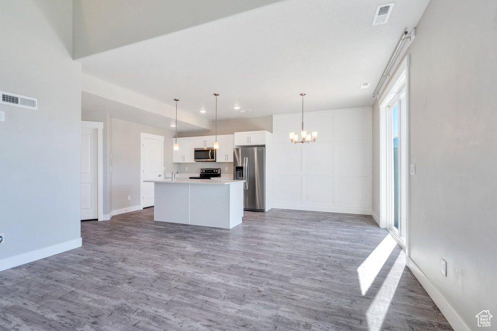 Unfurnished living room with a chandelier, baseboards, wood finished floors, and recessed lighting