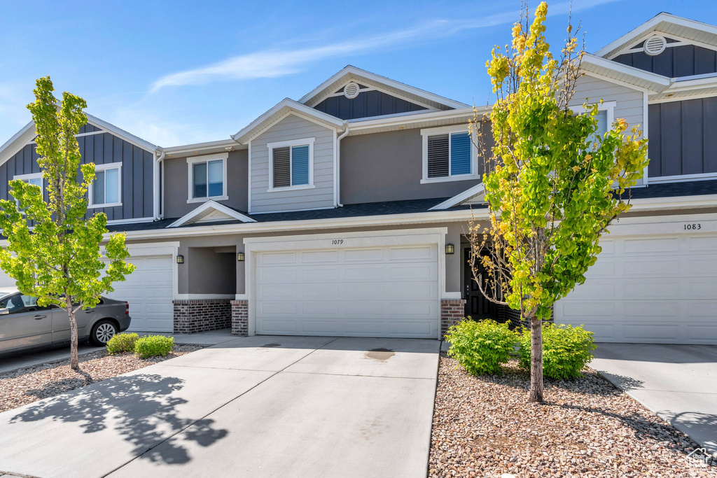 Townhome / multi-family property with board and batten siding, brick siding, a garage, and concrete driveway
