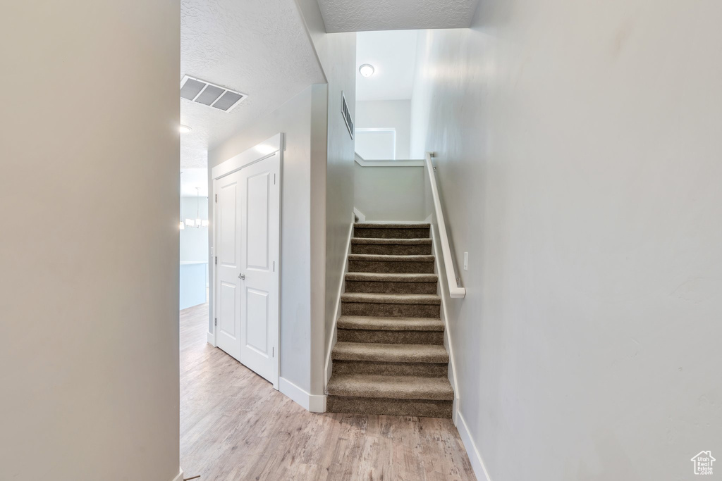Stairs featuring baseboards, wood finished floors, and a textured ceiling