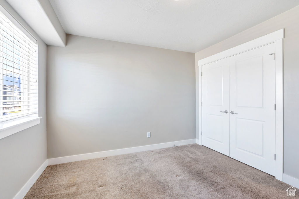 Unfurnished bedroom with carpet floors, baseboards, and a closet