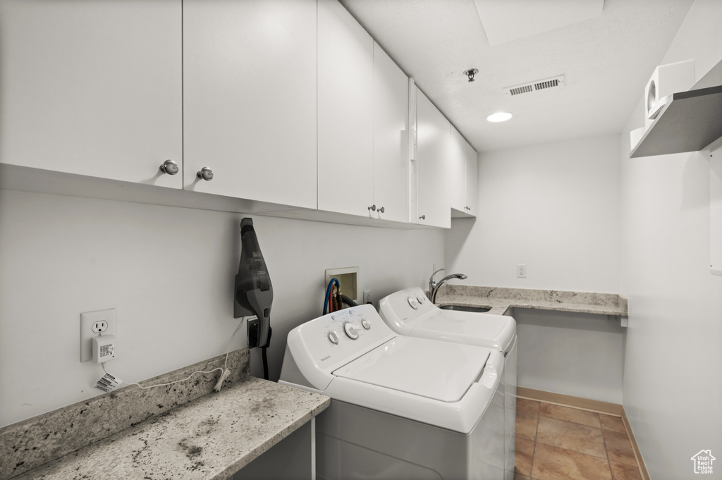 Laundry room featuring a sink, cabinet space, visible vents, washing machine and dryer, and baseboards