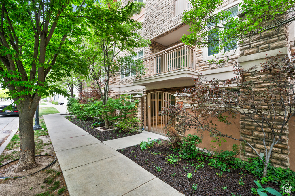 View of side of property featuring a gate, a fenced front yard, stone siding, and a balcony