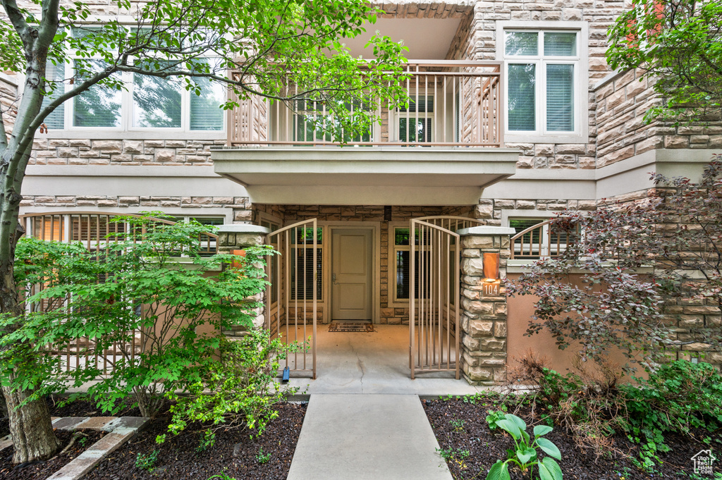 Doorway to property with a gate, stone siding, and a balcony