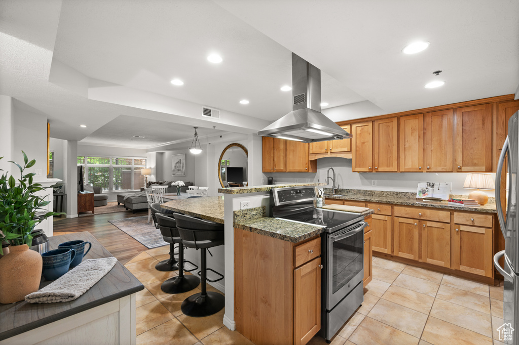 Kitchen with recessed lighting, visible vents, island exhaust hood, open floor plan, and appliances with stainless steel finishes