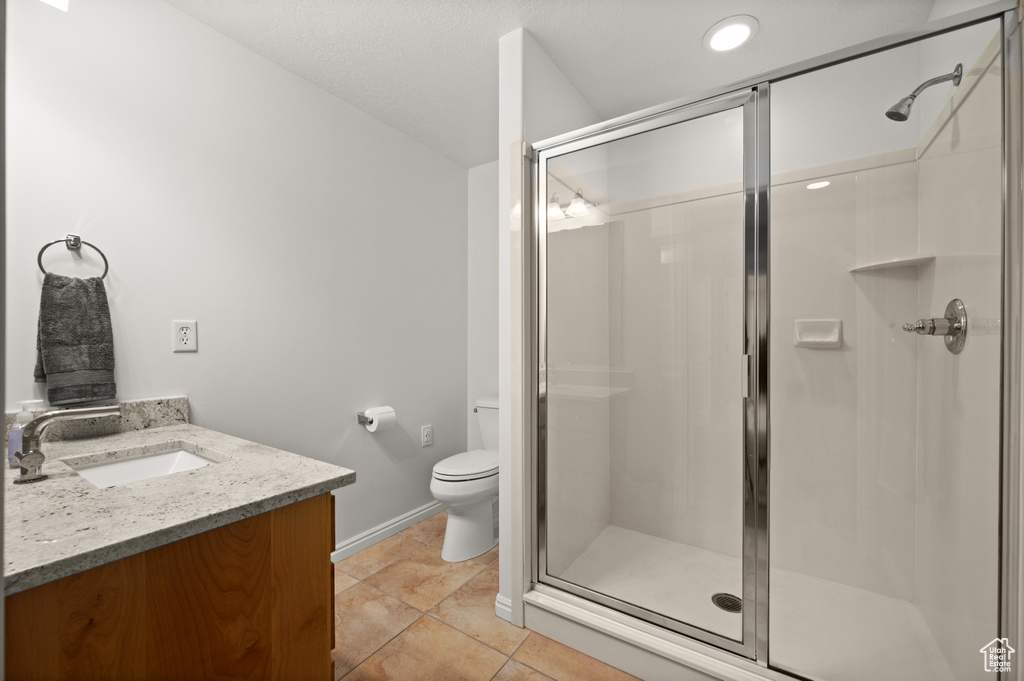 Full bath featuring a stall shower, vanity, toilet, and tile patterned flooring