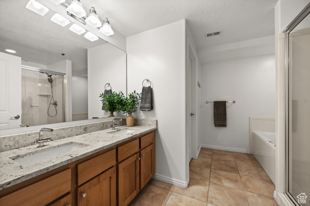 Full bathroom with double vanity, visible vents, a stall shower, and a sink
